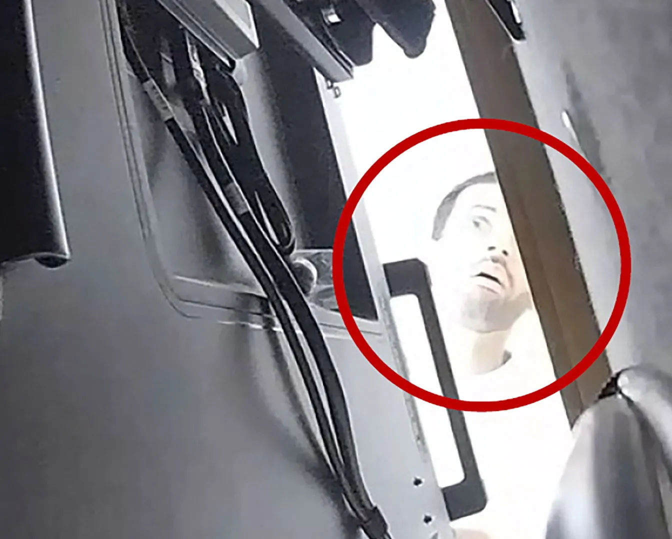 A man identified by federal prosecutors as Abdulrahman Alfozan looks behind a conference-room television; red circle marks his face