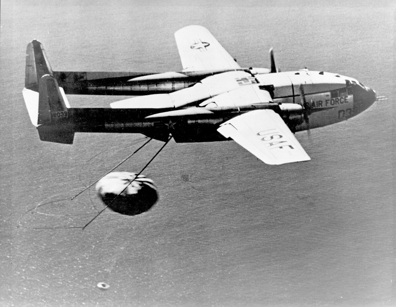 An Air Force C-119 aircraft catches the parachute of a descending CORONA film capsule over the Pacific