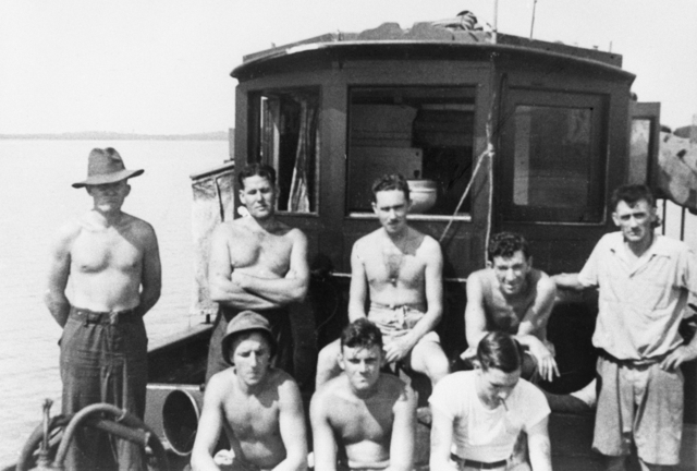 Allied raiders stand and sit on the cramped deck of MV Krait during Operation Jaywick