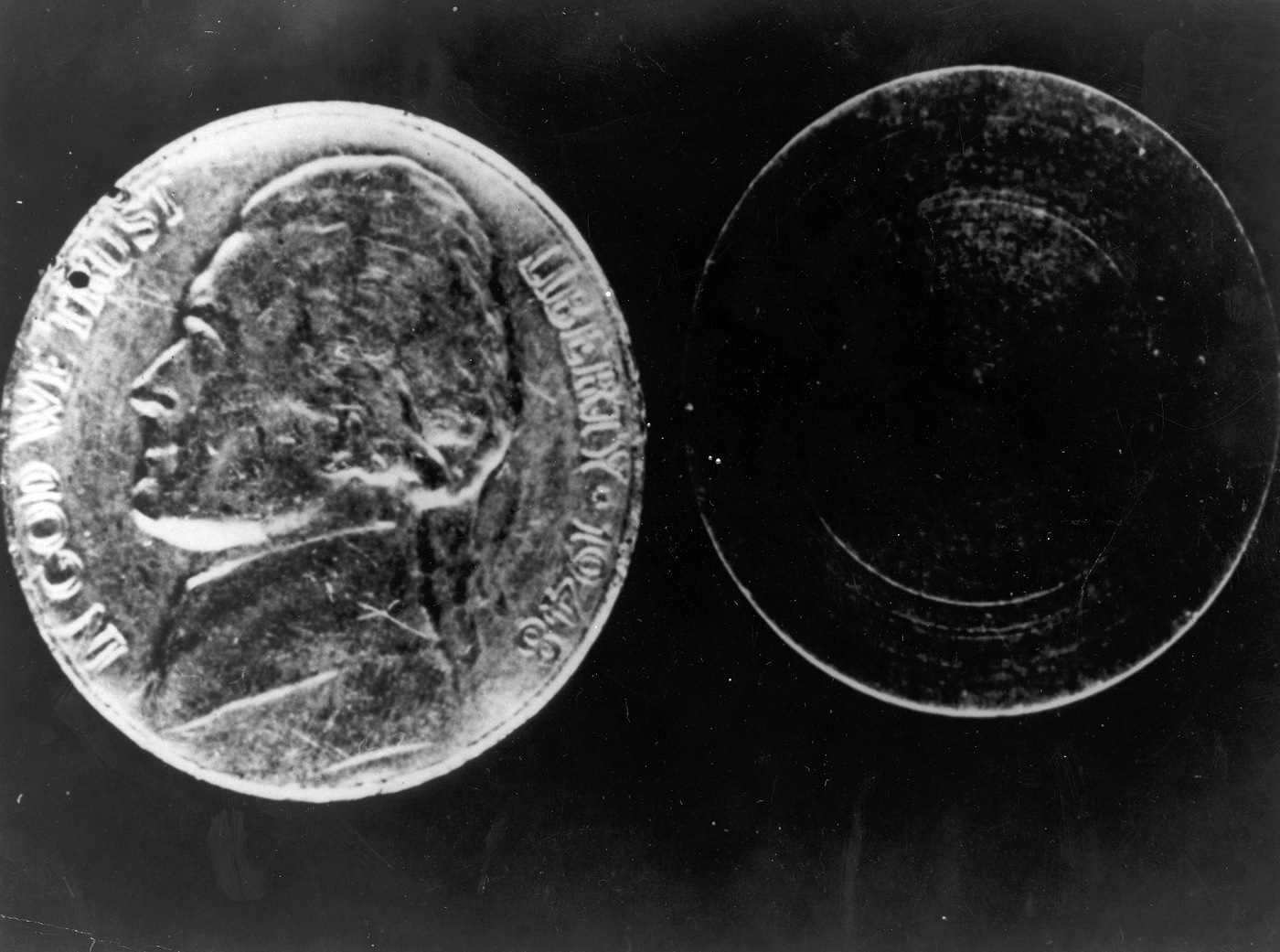 An opened hollow nickel beside the miniature coded message it concealed